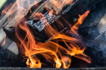 a Burning firewood in the fireplace close up, BBQ fire, charcoal background. Charcoal fire with sparks