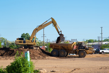 An excavator loads a truck with earth