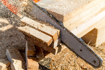 Close up of a woodcutter, sawing wooden boards chain saw in motion, sawdust fly to sides. Chainsaw in motion. Sawdust fly around.