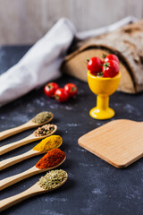 spoons with spices, paprika, basilic, pepper, thyme with cherry tomatoes