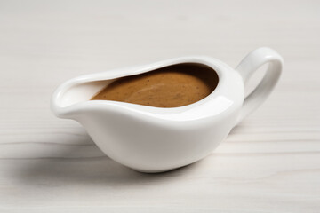 Delicious turkey gravy in sauce boat on white wooden table