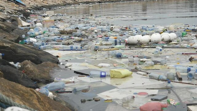 Environmental pollution. Plastic bottles, bags, trash in river, lake. Rubbish and pollution floating in water. Slow motion