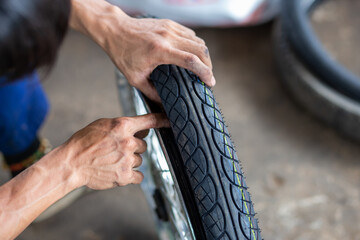 A close-up of the wheels of a motorbike is being removed by a mechanic to recap and change tires due to leaks.