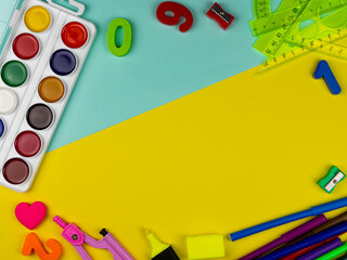 student's desk. Top view of the layout of school items. Rulers, paints, pencils and numbers on a yellow and blue background. Back to school
