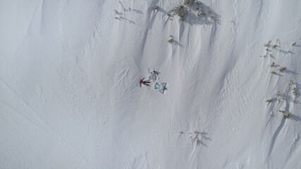top view of snow angels on a snow field in the mountains. snow angel - a man lies in the snow with his arms and legs outstretched by a star