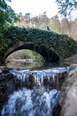 Fototapeta na wymiar Small waterfall under an old bridge in a park in Bristol, UK
