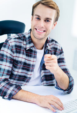 Portrait of happy smiling man in casual smart clothing, pointing at you, indoors. Success in business, job concept.