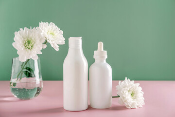 Mock up natural cosmetics: serum, cream, mask for advertising on green background with flowers. Organic products.