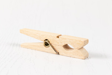 wooden clothespin with metal spring on the background of a white wooden table. close-up. selective focus