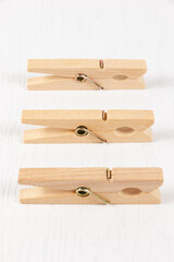 three wooden clothespins with a metal spring on the background of a white wooden table. close-up. selective focus