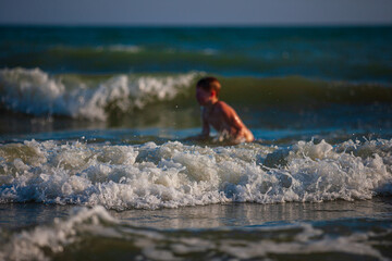 Boy on the beach, playing with the waves, summer time