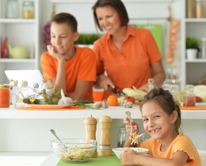 Obraz na płótnie Canvas Cute girl eating delicious fresh salad in kitchen