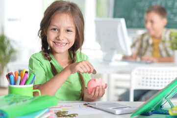 Cute teen girl putting coins in piggy bank