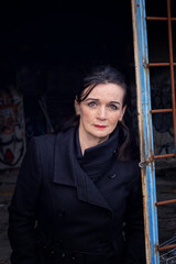 portrait of woman in her 50s standing at abandoned building