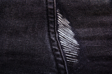 Hole on dark denim jeans. Demaged fabric texture