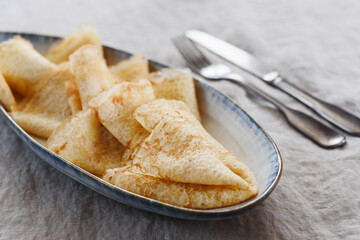 Breakfast with crepes or pancakes and jam, juice and tangerine on greige linen tablecloth. Pancake week or Shrovetide. Selective focus