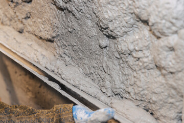 The final stage of plastering the walls. A worker levels the plaster with a leveler.