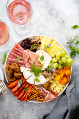 Charcuterie plate, variety of cheeses and salami, prosciutto, dried fruits, figs, apricots, cranberries served with two glasses of wine.