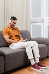 pleased man chatting on cellphone while listening music in wireless headphones