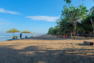 Kuta, Bali, Indonesia (2 May 2021): Kuta beach in the morning. There are sand, lazy chairs, beach, sky and some local people are doing morning activity