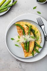 omelet with asparagus, pesto and cheese on a white plate