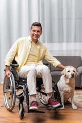 disabled man in wheelchair smiling at camera while petting labrador dog
