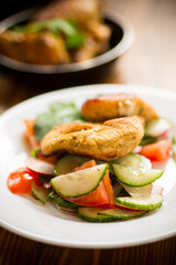 fried chicken fillet with fresh cucumbers, tomatoes and radishes in a plate