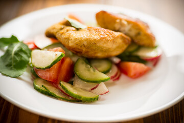 fried chicken fillet with fresh cucumbers, tomatoes and radishes in a plate