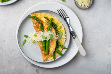 omelet with asparagus, pesto and cheese on a white plate