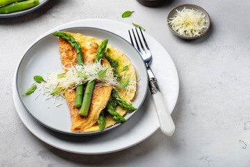 omelet with asparagus, pesto and cheese on a white plate