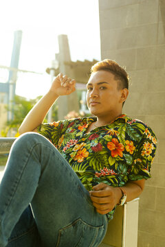 Joven gay de la selva peruana posando en el parque de su ciudad con una camisa con flores