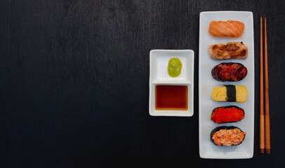 Fototapeta na wymiar The sushi set is a famous Japanese dish, put on a ceramic plate, beautifully arranged on a black background.