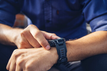 businessman wearing digital smart watch in hand  touching screen to open notification, read message and activity tracker in wrist with soft-focus and over light in the background.