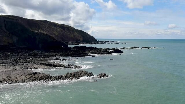 Aerial coastal shot of the waves in the sea at Spekes Mill beach in Devon UK