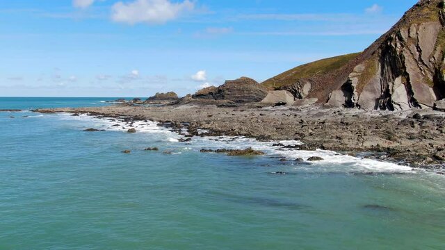 Aerial coastal shot of the waves in the sea and rocks at Spekes Mill beach in Devon
