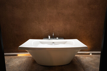 Fototapeta na wymiar Elegant white ceramic bathtub with bubble in natural earth bathroom