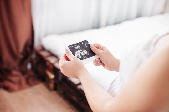 Pregnant woman looks at ultrasound photo