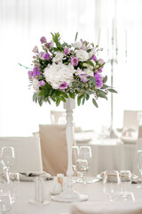 Centerpiece made of green leaves and fresh flowers stands on the dinner table. Wedding day. Fresh flowers decorations.