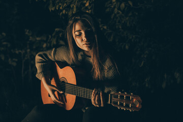 Belle fille avec une guitare au coin du feu