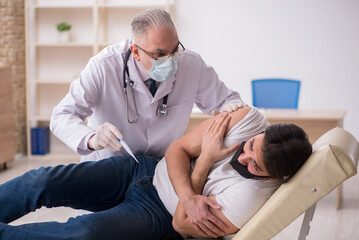 Young male patient visiting old doctor in vaccination concept