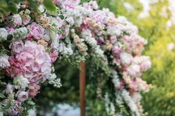 Obraz premium Close up of very beautiful and stylish wedding arch, decorated with various fresh flowers, standing in the garden.