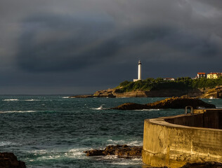 Harbor at Biarritz, France, on a stormy night with a lighthouse in the distance