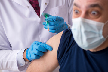 Old male patient visiting young male doctor in vaccination conce