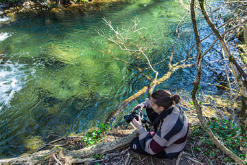 young girl taking long exposure photographs of forest river water