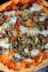 Pizza with mushrooms, sausage and olives on a wooden background