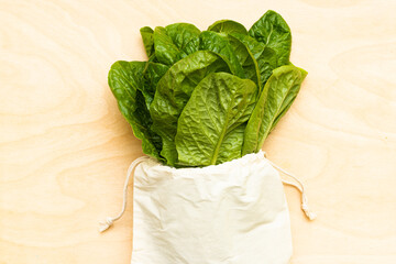 Salad Lettuce in eco bag on wooden background zero waste concept