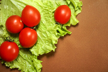 Red cherry tomatoes lie on a lettuce leaf.