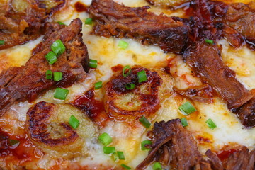 Pizza with mushrooms, sausage and olives on a wooden background