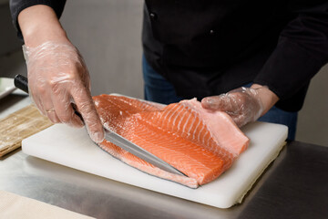 The process of preparing delicious fish dishes. Japanese restaurant cuisine. The sushi chef holds a...