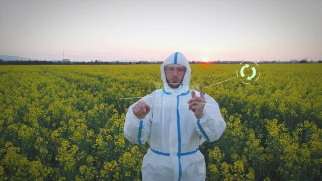 Agricultural scientist protected from plant toxins in protective suit checks development of plants with modern tablet. Digital HUD elements for control.